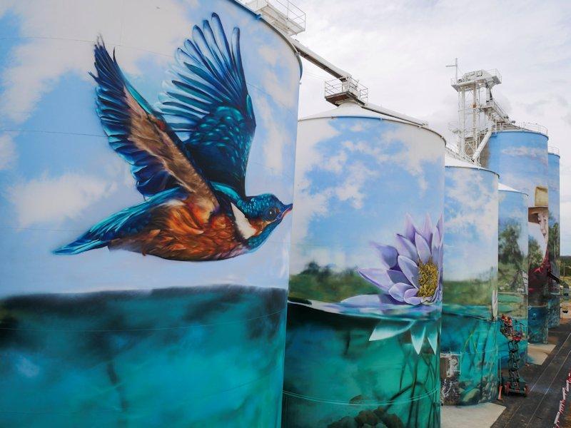 final stage of the yelarbon silo artwork completed featuring kingfisher flying over lagoon and water lily in the lagoon in shades of blue and green